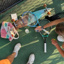 tennis racquets and a skateboard on the ground of a tennis court 