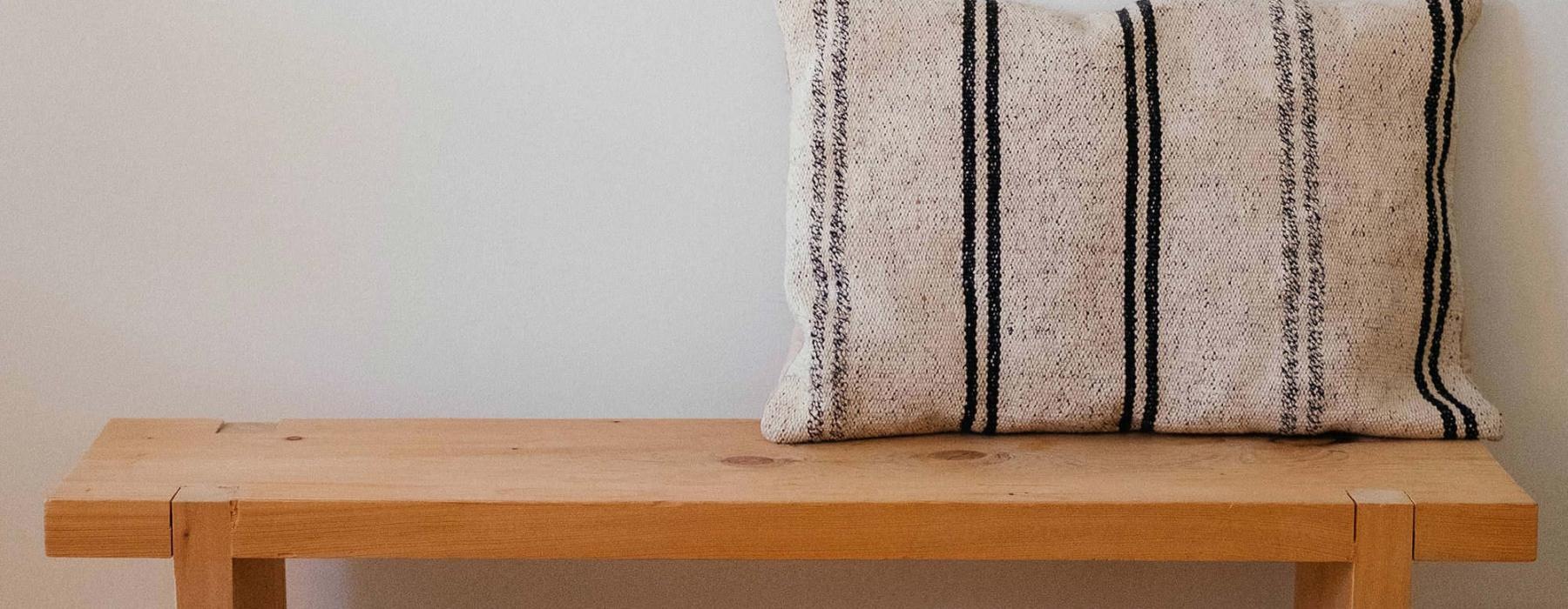 a wooden bench with a striped pillow on it
